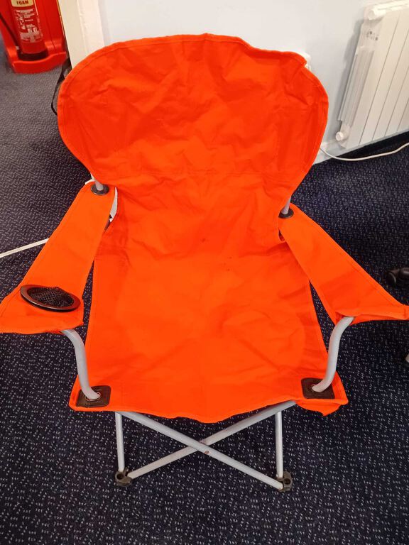 Orange folding camping chair in carry bag